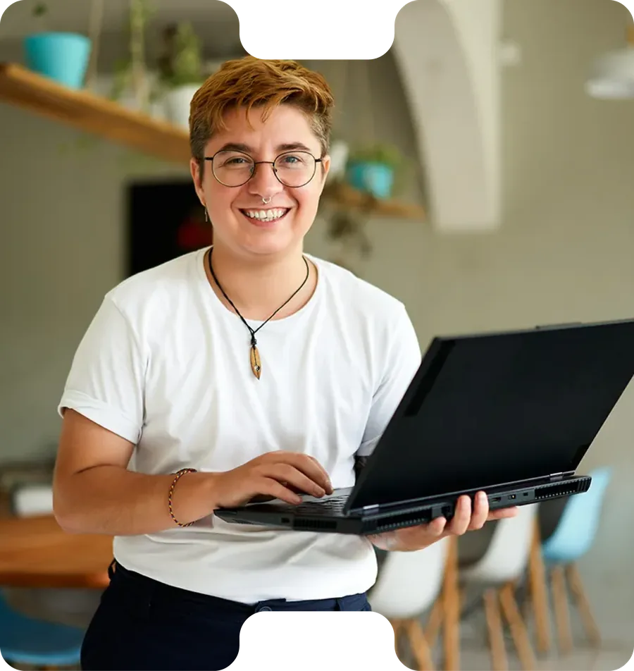 A smiling person holding a laptop