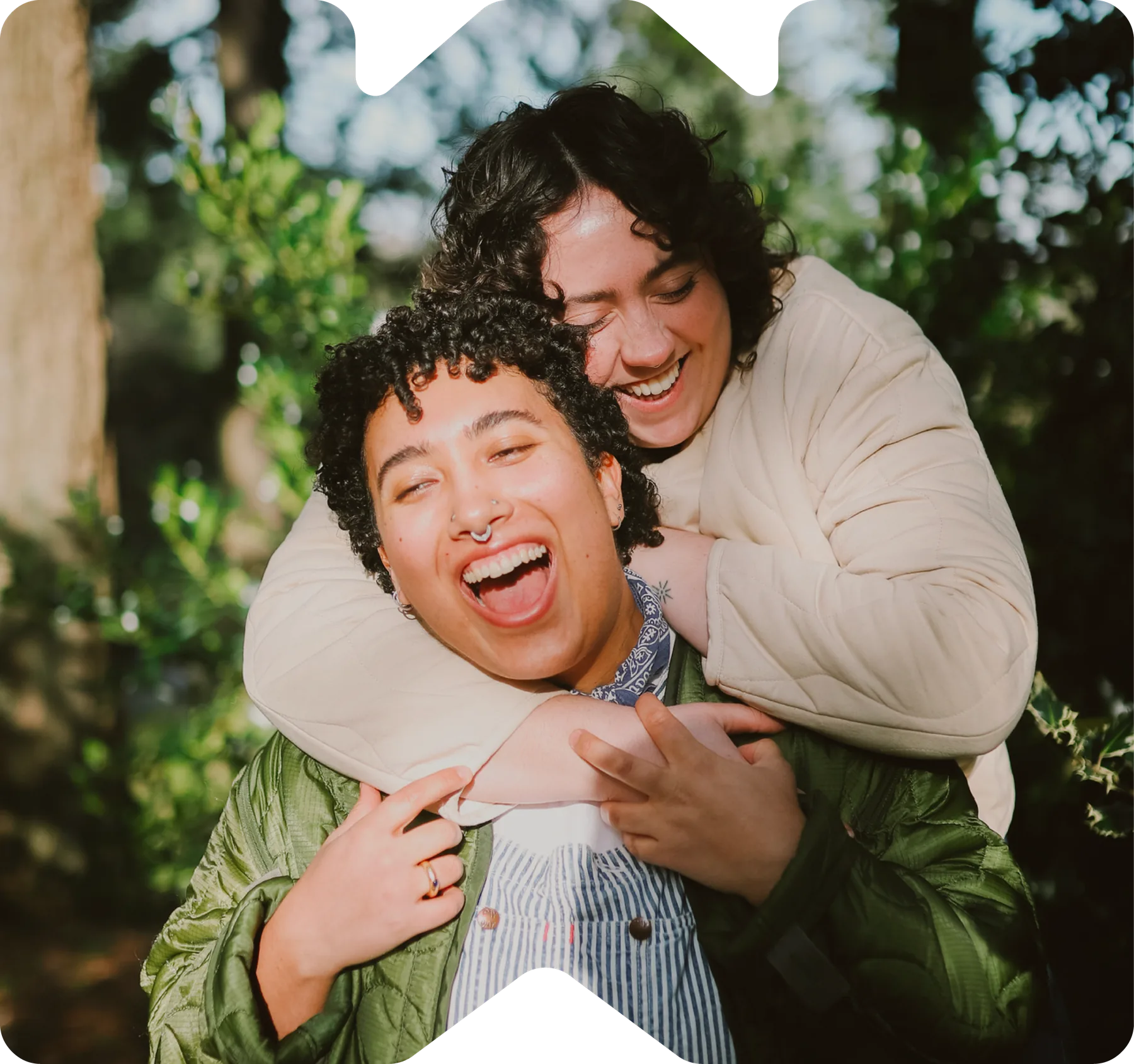 Two friends laughing and hugging outdoors